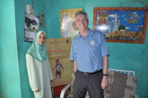 Rotarian Chris Offer (right) and Dr. Noha Farag from the CDC visit a traditional healer's hut as part of a polio surveillance team in Sudan. A Rotary poster about paralysis appears in the background.