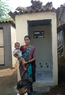 A woman stands in front of her toilet block in Sogav, India.