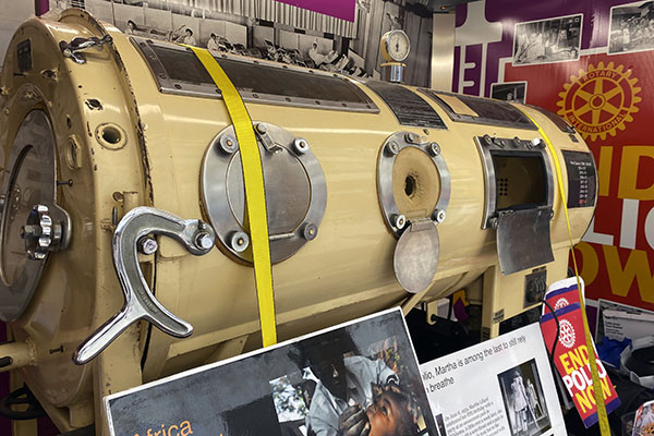 An iron lung sits inside a mobile exhibit with other decorations around it